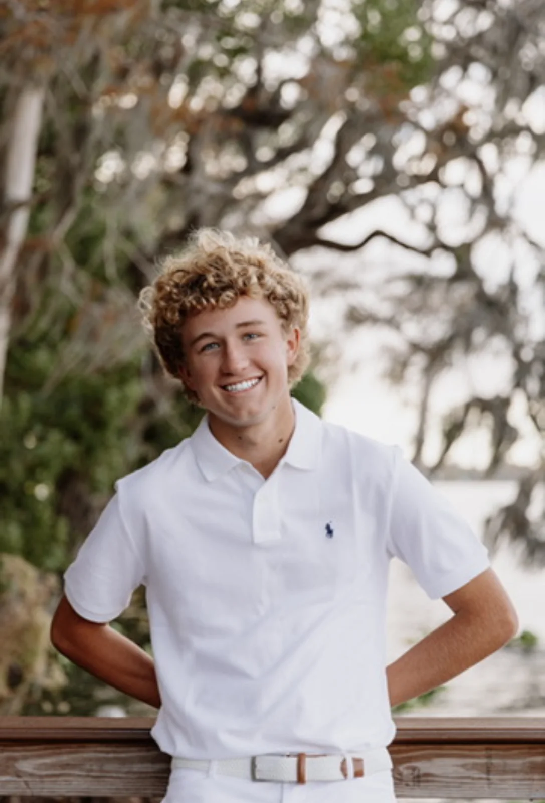 Peter Sirianni smiling in a white polo beneath the trees